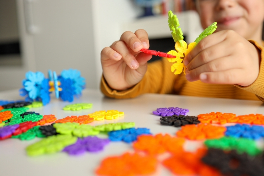 A young child building with interlocking disc toys, developing fine motor skills and creativity through early childhood education play.
